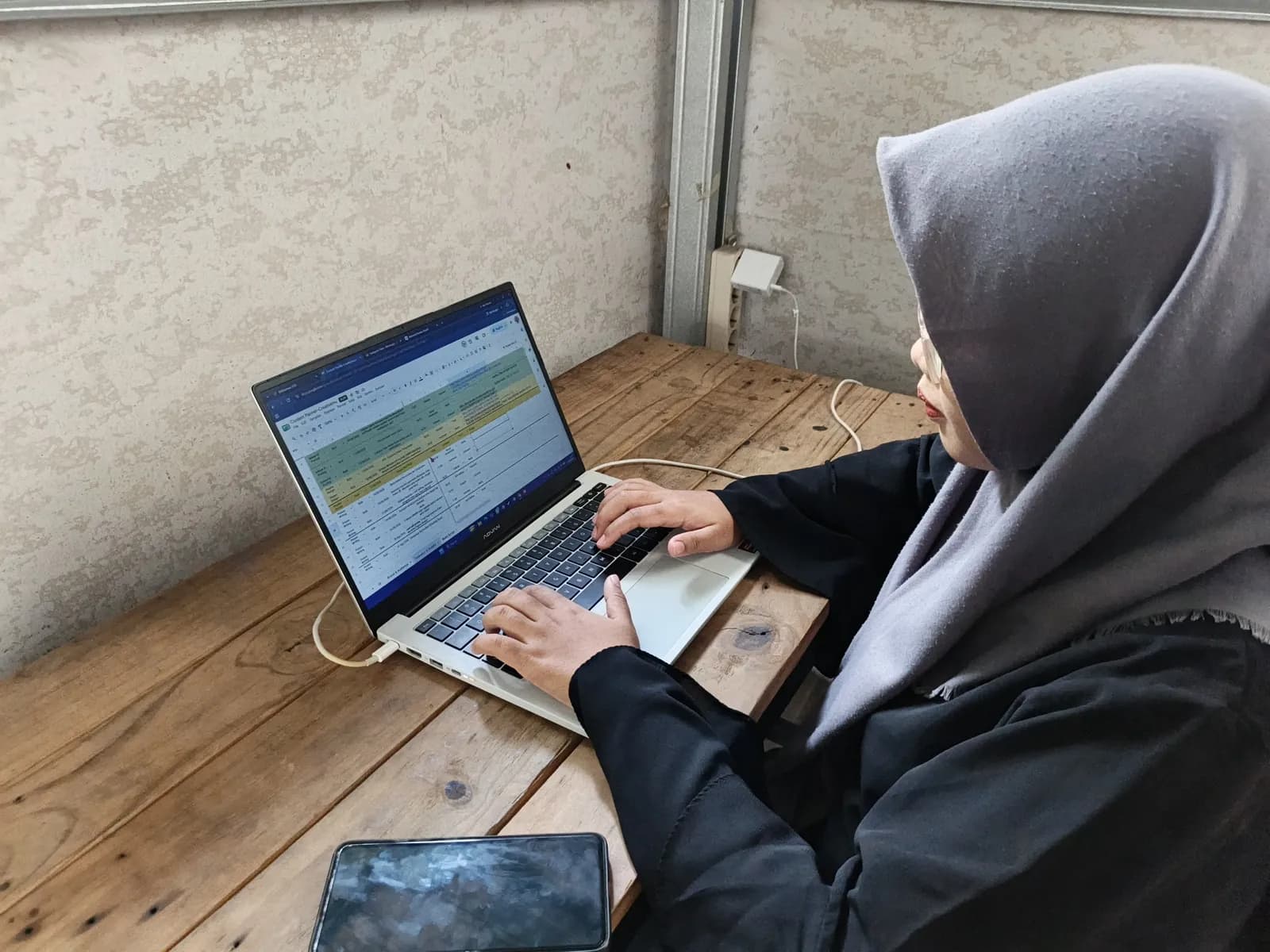 Peserta mengetik di laptop yang menampilkan tabel rencana