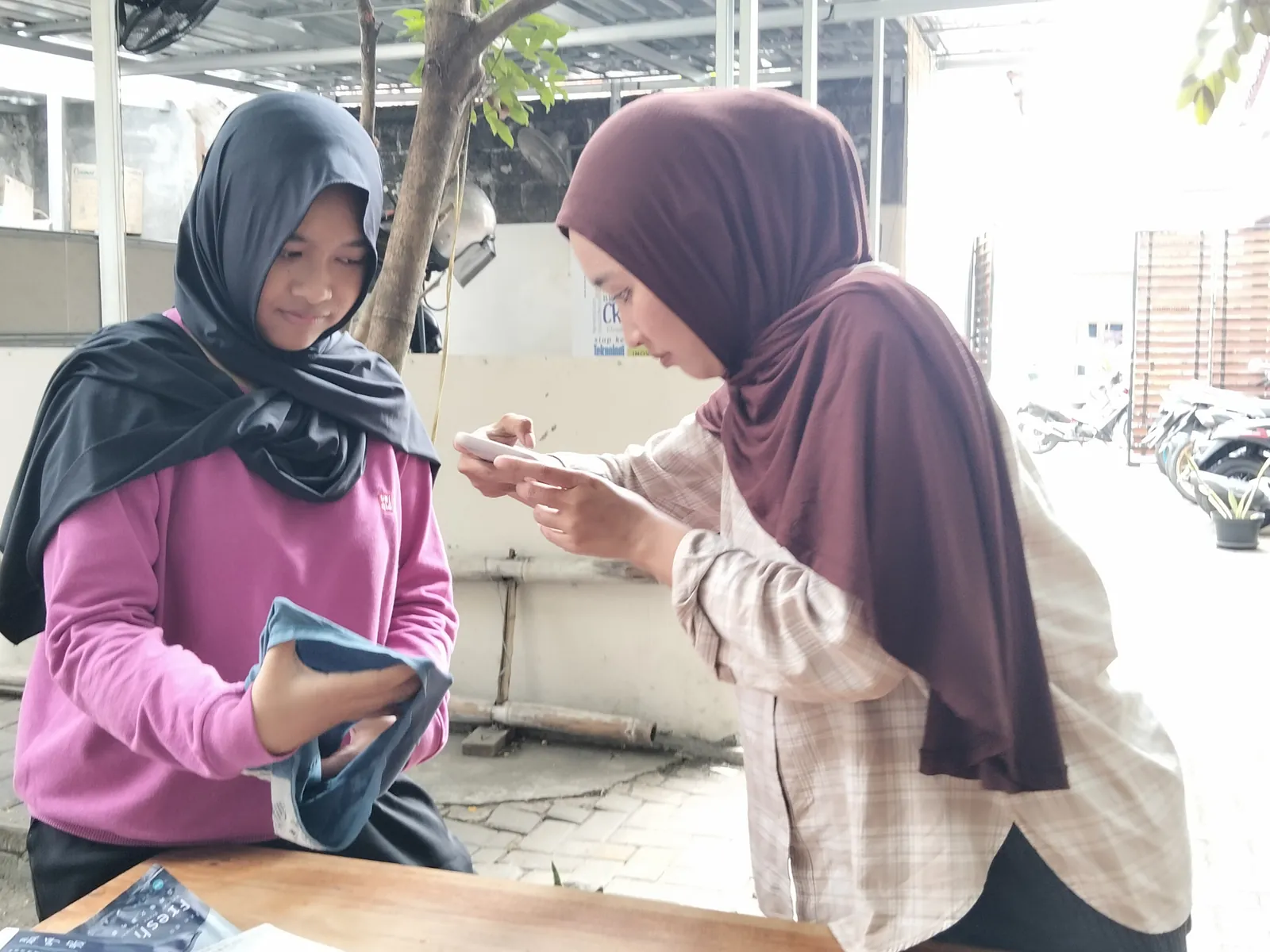 Dua peserta menata produk di area terbuka kantor
