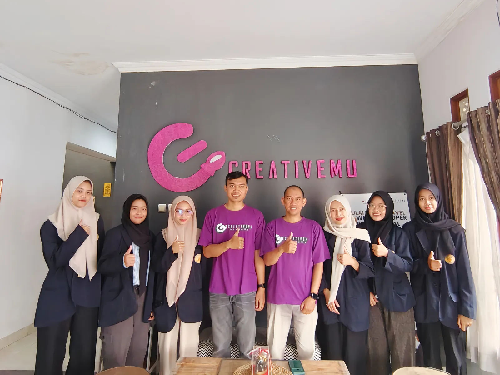 Peserta magang berfoto bersama di depan logo Creativemu